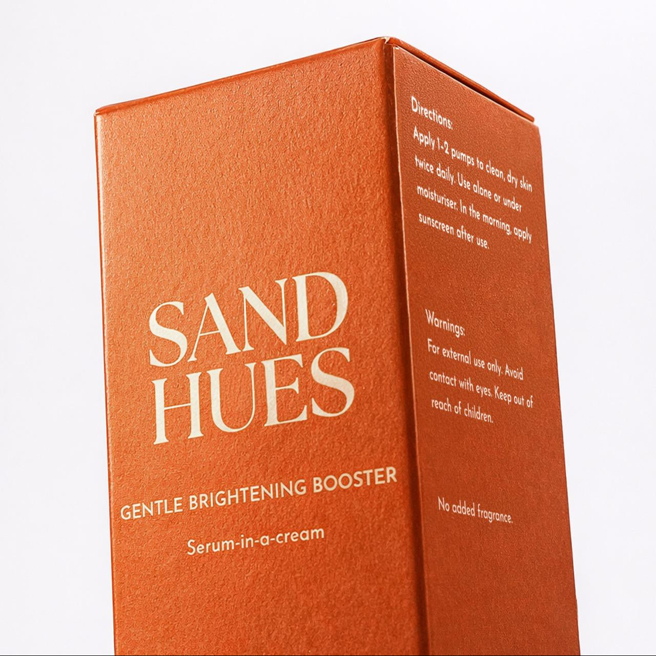 Orange packaging of Sand Hues Gentle Brightening Booster with text on a white background